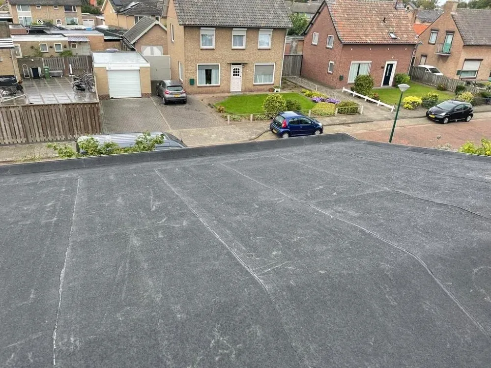 Plat dak met bitumineuze dakbedekking, met uitzicht over een woonstraat
